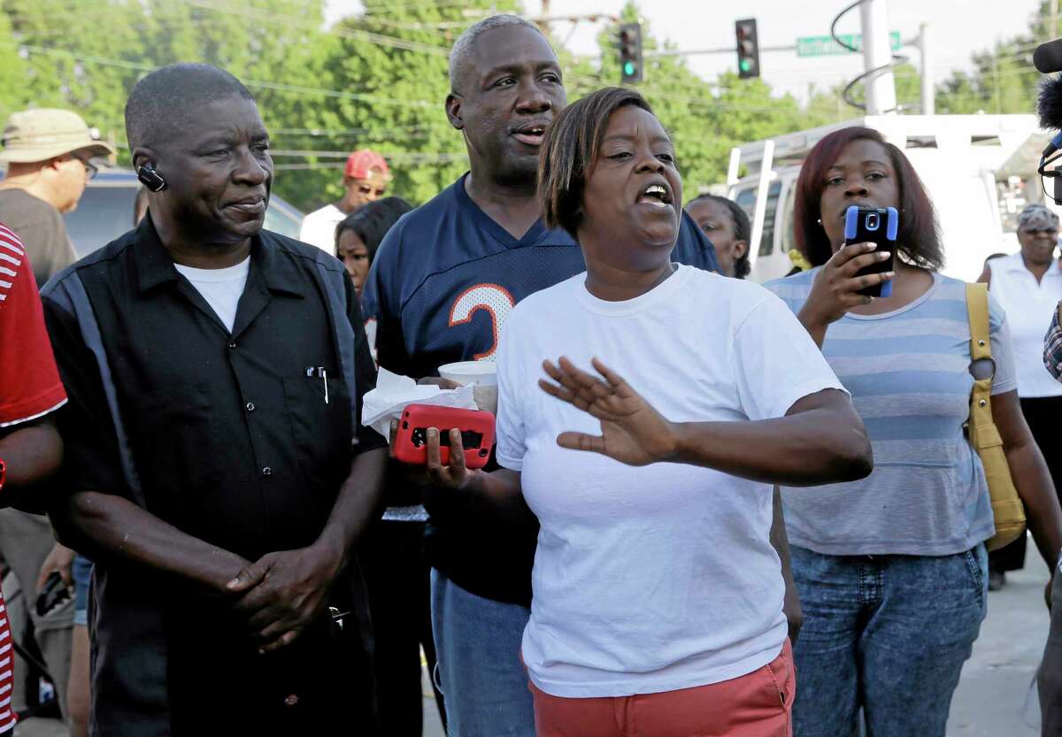 People react after Ferguson Police Chief Thomas Jackson releases the name of the the officer accused of fatally shooting Michael Brown, an unarmed black teenager, Friday, Aug. 15, 2014, in Ferguson, Mo. The officer’s name is Darren Wilson, a six-year veteran of the force.