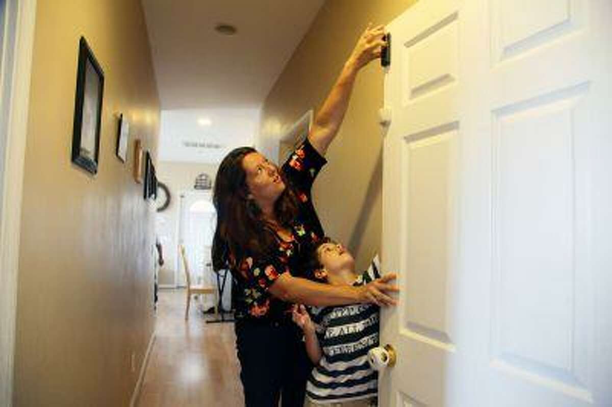 Jo Ashline sets a door lock, accompanied by her son, Andrew, 11, who has autism, at their home in Orange, Calif. on Friday, Aug. 9, 2013. Ashline says, "We take steps at home, locks on every door, gates, alarms but there's always, in the forefront of our minds, the thought that one tiny mistake could prove fatal." The phenomenon goes by various names - wandering, elopement, bolting - and about half of autistic children are prone to it, according to research published in 2012 in the journal Pediatrics. It has claimed the lives of more than 60 children in the past four years and can make daily life a harrowing, never-let-your-guard-down challenge for parents whose sons and daughters are at risk.
