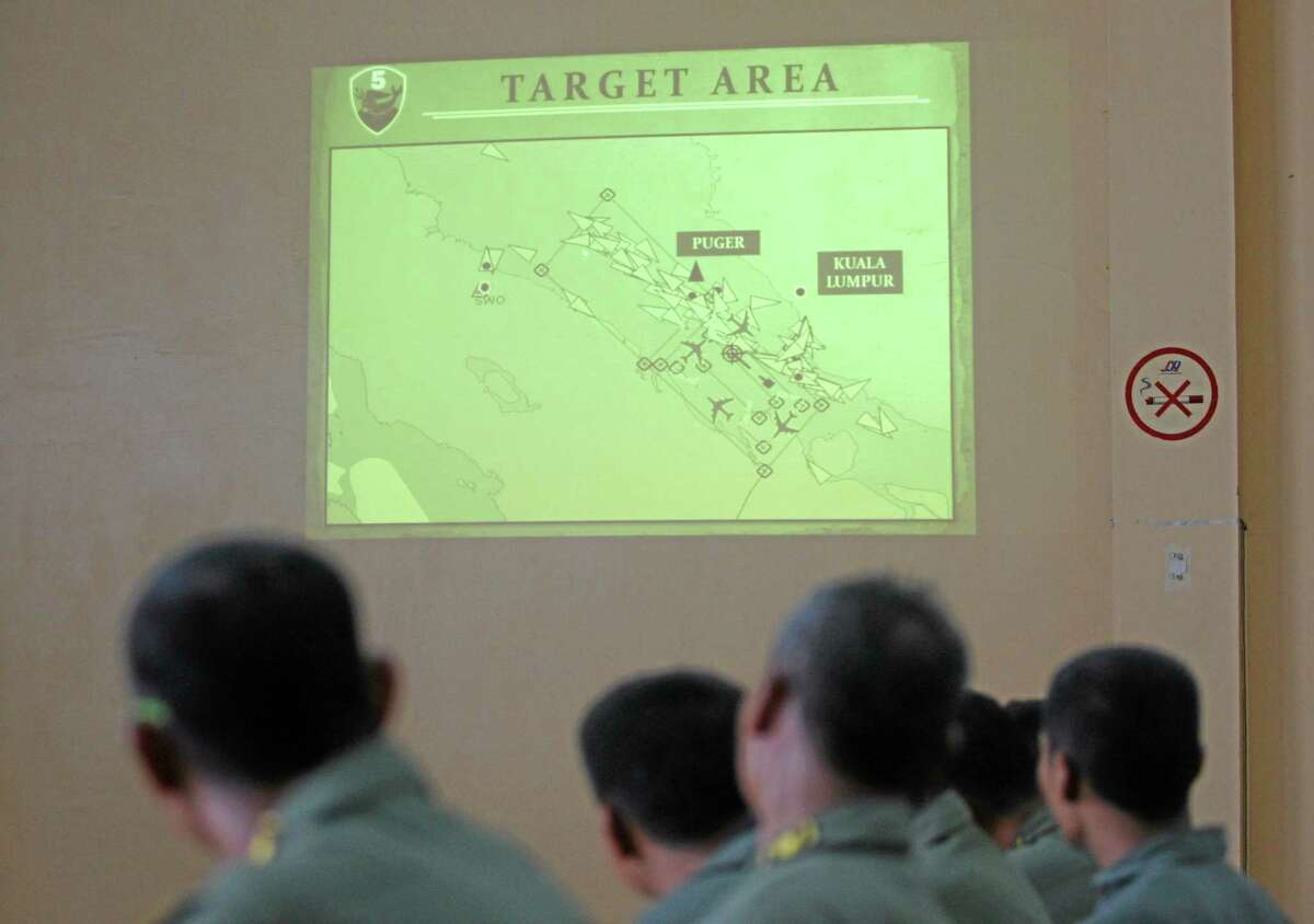 Indonesian Air Force personnel of the 5th Air Squadron "Black Mermaids" listen to a briefing as an operation map is projected on the wall following a search mission for the missing Malaysia Airlines Boeing 777 that was conducted over the Strait of Malacca, at Suwondo air base in Medan, North Sumatra, Indonesia, Friday, March 14, 2014. The jetliner vanished nearly a week ago with 239 people aboard. (AP Photo/Binsar Bakkara)