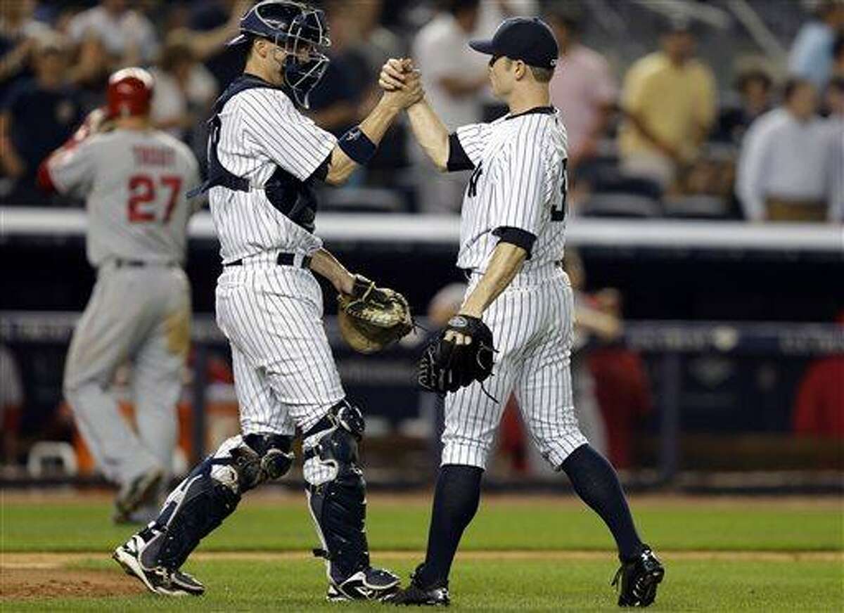 Los Angeles Angels' Mike Trout, far right, heads to the dugout as New York Yankees catcher Chris Stewart (19) congratulates relief pitcher David Robertson (30) who closed out the Yankees 2-1 victory in their baseball game, Monday, Aug. 12, 2013, in New York. (AP Photo/Kathy Willens)