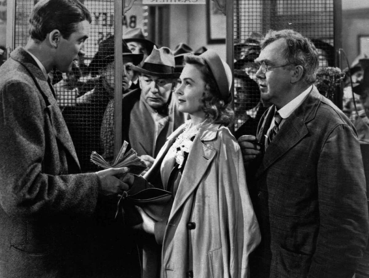 In this undated file photo James Stewart, left, Thomas Mitchell, right, and Donna Reed appear in a scene from the 1946 film "It's A Wonderful Life." Folks in Seneca Falls, N.Y., think Bailey's make-believe hometown, Bedford Falls in the movie, was heavily inspired by their quaint upstate town. This cannot be proven, and director Frank Capra never confirmed such a connection, but that hasn't stopped locals in Seneca Falls from celebrating the beloved movie every December. (AP Photo, File)
