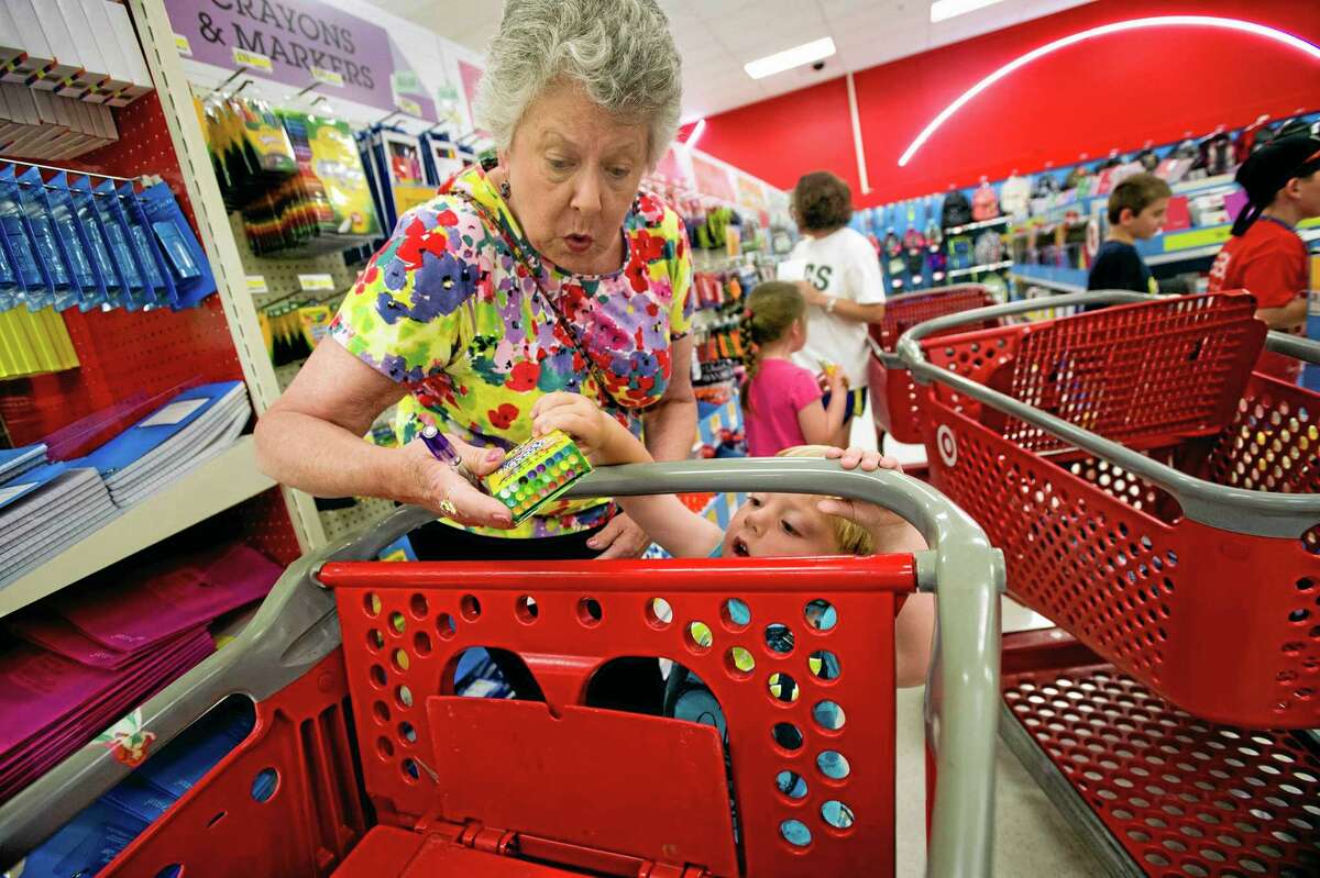 In this July 23 photo, Julie Wilkins helps her grandson, Griffin Brady, 3, put a box of crayons in a shopping cart while shopping for school supplies with her family at a Target store in Memphis, Tennessee.