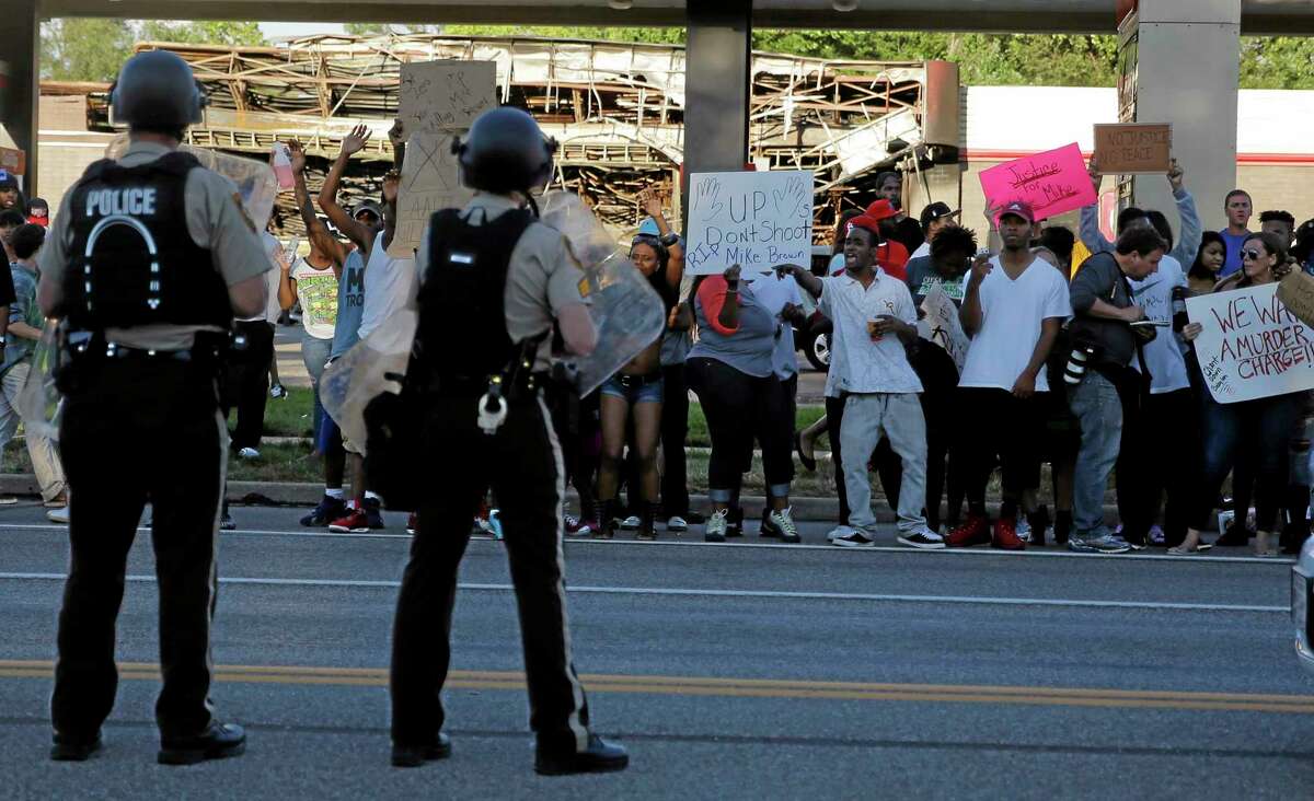 Protesters yell at police Tuesday, Aug. 12, 2014, in Ferguson, Mo. The Rev. Al Sharpton pressed police Tuesday to release the name of the officer who fatally shot an unarmed teenager in suburban St. Louis, and he pleaded for calm after two nights of violent protests over the young man’s death.