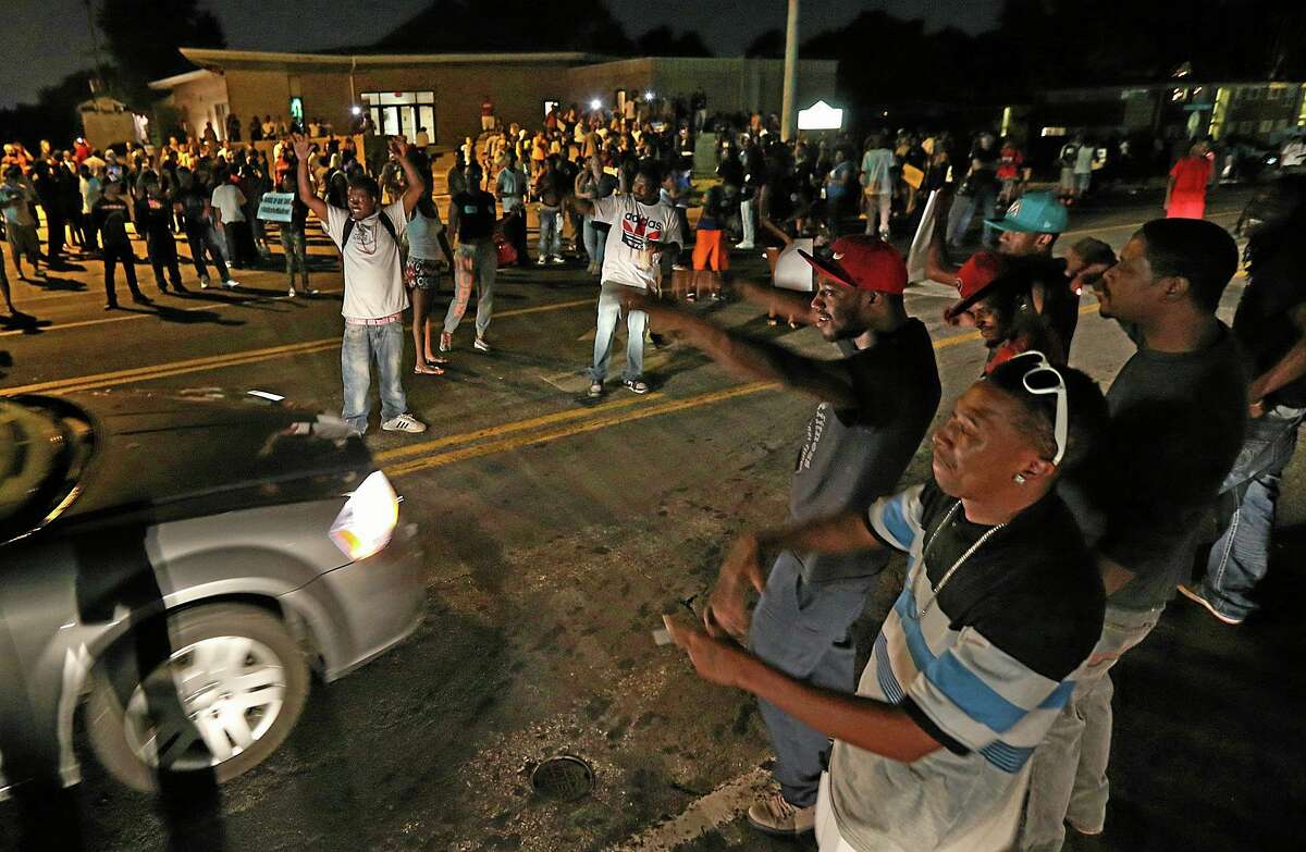 A group demonstrates along and in the middle of Chambers Rd. outside the Greater St. Mark Missionary Baptist Church after the conclusion of a gathering with Michael Brown’s family and Rev. Al Sharpton on Tuesday, Aug. 12, 2014, in Dellwood.
