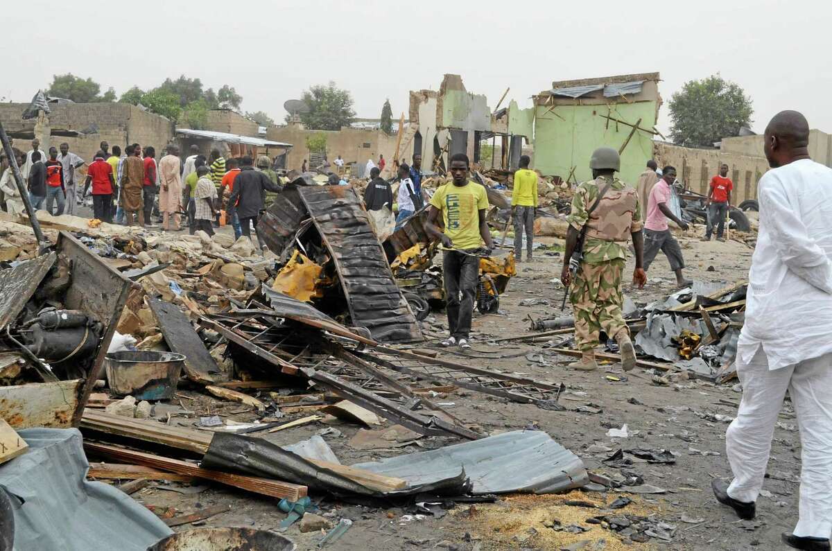 People gather at the site of a twin car bomb explosion in Maiduguri, Nigeria, Sunday, March 2, 2014. Twin car bomb blasts at a bustling marketplace killed at least 51 people in Maiduguri, the northeast Nigerian city that is the birthplace of Nigeria's Islamic extremist terrorist group, a Red Cross official said Sunday. (AP Photo/Jossy Ola )