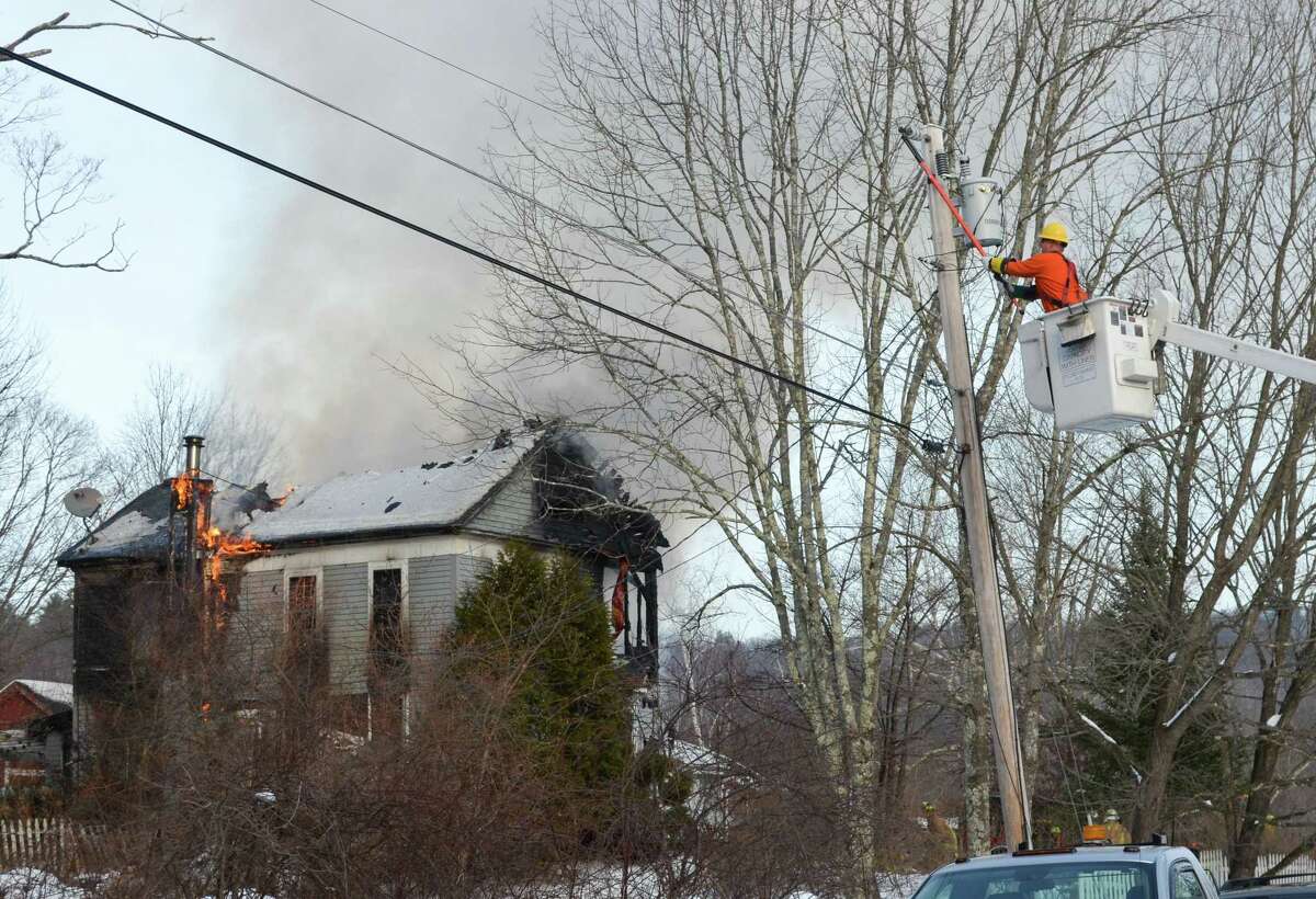 A Connecticut Light and Power worker cuts electricity to a fully-involved fire at a house at Sugar Shack Farm, near the intersection of Ashley Road and Blue Street in Winchester Thursday afternoon.