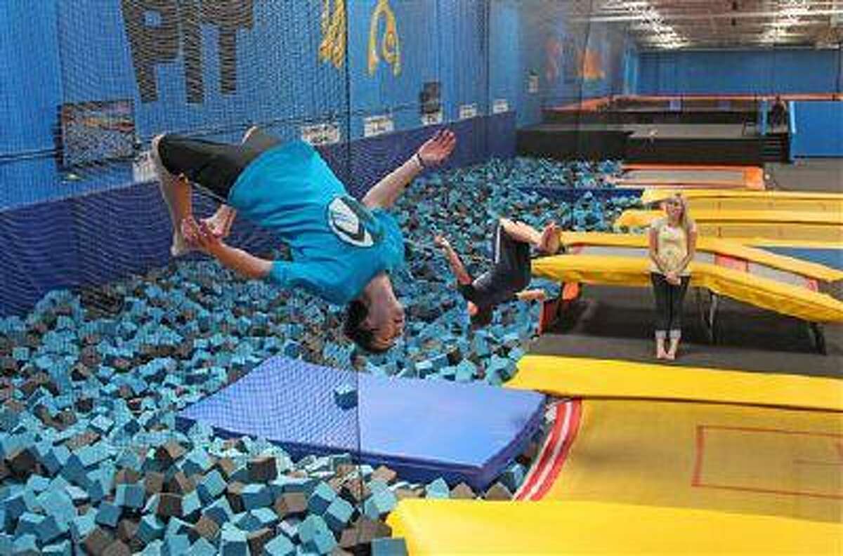 In this July 31, 2013, photo, Hunter Gottfredson, left, 15, of Elk Ridge, flips at the Get Air Hang Time indoor trampoline park in Orem, Utah. Indoor trampoline parks have cropped up around the country in recent years, offering customers a chance to bounce, flip and jump in wall-to-wall trampolines. The jump gyms offer the kind of rain-or-shine suburban entertainment popular for birthday parties and summer camps. But some doctors and officials say the parks are dangerous and can cause serious injuries. (AP Photo/Rick Bowmer)
