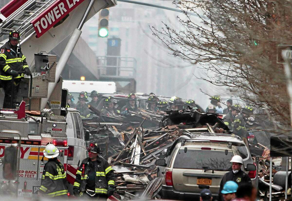 Firefighters continue to investigate and remove debris from an explosion in Harlem, Wednesday, March 12, 2014 in New York. A gas leak triggered an explosion that shattered windows a block away, rained debris onto elevated commuter railroad tracks close by, cast a plume of smoke over the skyline and sent people running into the streets. (AP Photo/Bebeto Matthews)