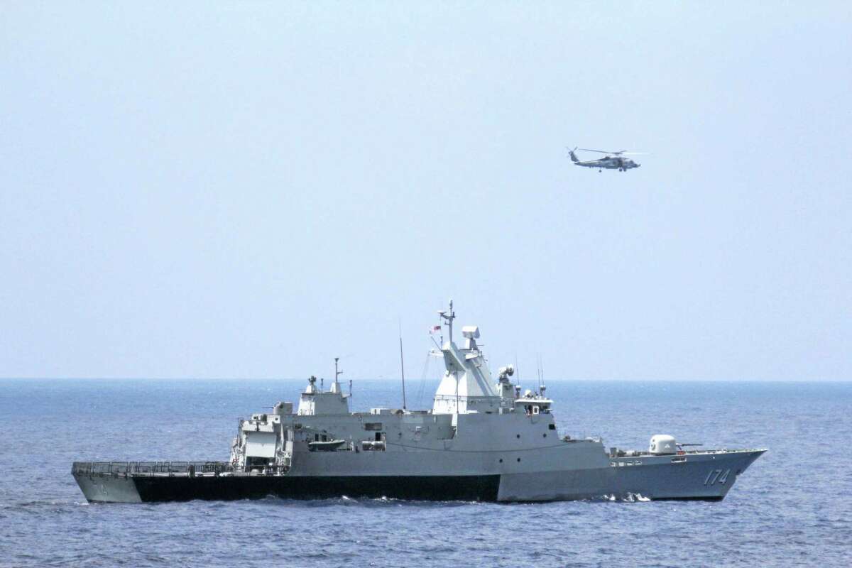 This photo provided by the U.S. Navy shows the Royal Malaysian Navy corvette KD Terengganu and a U.S. Navy MH-60R Sea Hawk helicopter conduct a coordinated air and sea search for a missing Malaysian Airlines jet in the Gulf of Thailand. (AP Photo/U.S. Navy, Operations Specialist 1st Class Claudia Franco)