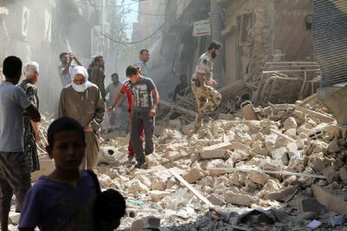 Residents of Syria's eastern town of Deir Ezzor walk past the debris of a building reportedly hit by a missile on September 26. The Syrian Observatory for Human Rights said on September 14, that there was fighting between rebels and units of the jihadist Islamic State of Iraq and the Levant (ISIS) in Albu Kamal, with five people killed.