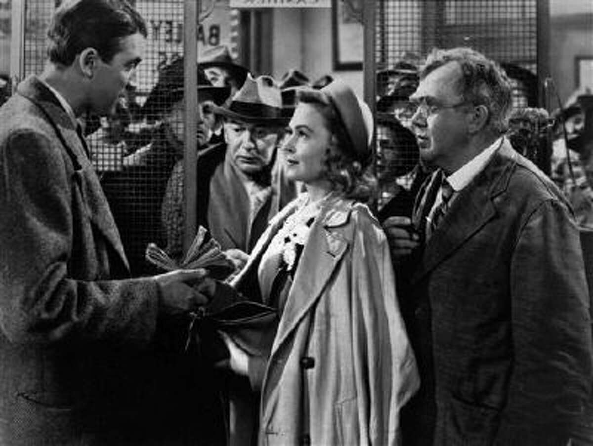 In this undated file photo James Stewart, left, Thomas Mitchell, right, and Donna Reed appear in a scene from the 1946 film "It's A Wonderful Life." Folks in Seneca Falls, N.Y., think Bailey's make-believe hometown, Bedford Falls in the movie, was heavily inspired by their quaint upstate town. This cannot be proven, and director Frank Capra never confirmed such a connection, but that hasn't stopped locals in Seneca Falls from celebrating the beloved movie every December.
