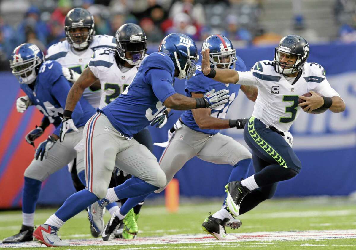 Seahawks quarterback Russell Wilson stiff-arms New York Giants defensive end Justin Tuck (91) during the second half of Seattle’s 23-0 win on Sunday in East Rutherford, N.J.