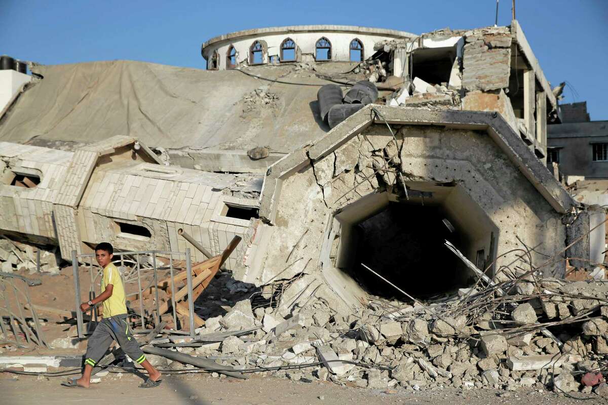A Palestinian boy walks by the rubble of the toppled minaret of the Abu Jihad Al Wazer mosque, destroyed by an Israeli strike during the war, in Gaza City, Monday, Aug. 11, 2014. (AP Photo/Lefteris Pitarakis)
