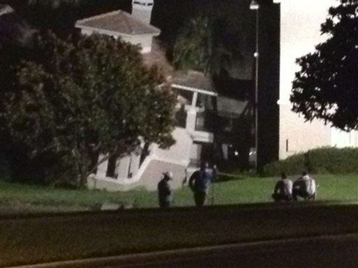 In this video frame grab image taken from WFTV television, police officers look on a hotel building after its foundation cracked in Clermont, Fl., early Monday, Aug. 12, 2013. A sinkhole caused a section of a central Florida resort villa to partially collapse early Monday, while another section of the villa was sinking, authorities said. About 30 percent of the three-story structure collapsed around 3 a.m. Monday, Lake County Fire Rescue Battalion Chief Tony Cuellar said. No injuries were reported. (AP Photo/WFTV/Myrt Price) MANDATORY CREDIT, ORLAND OUT