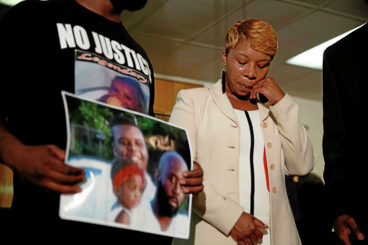 Lesley McSpadden, the mother of 18-year-old Michael Brown, wipes away tears as Brown’s father, Michael Brown Sr., holds up a family picture of himself, his son, top left, and a young child during a news conference Monday, Aug. 11, 2014, in Ferguson, Mo.