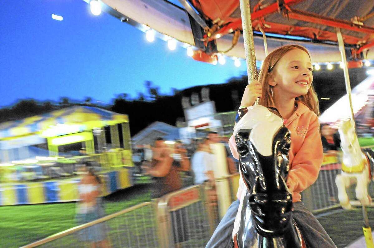 Mariah Walker, 7, of Winsted, rides the carousel at the 2013 Fireman’s Carnival.
