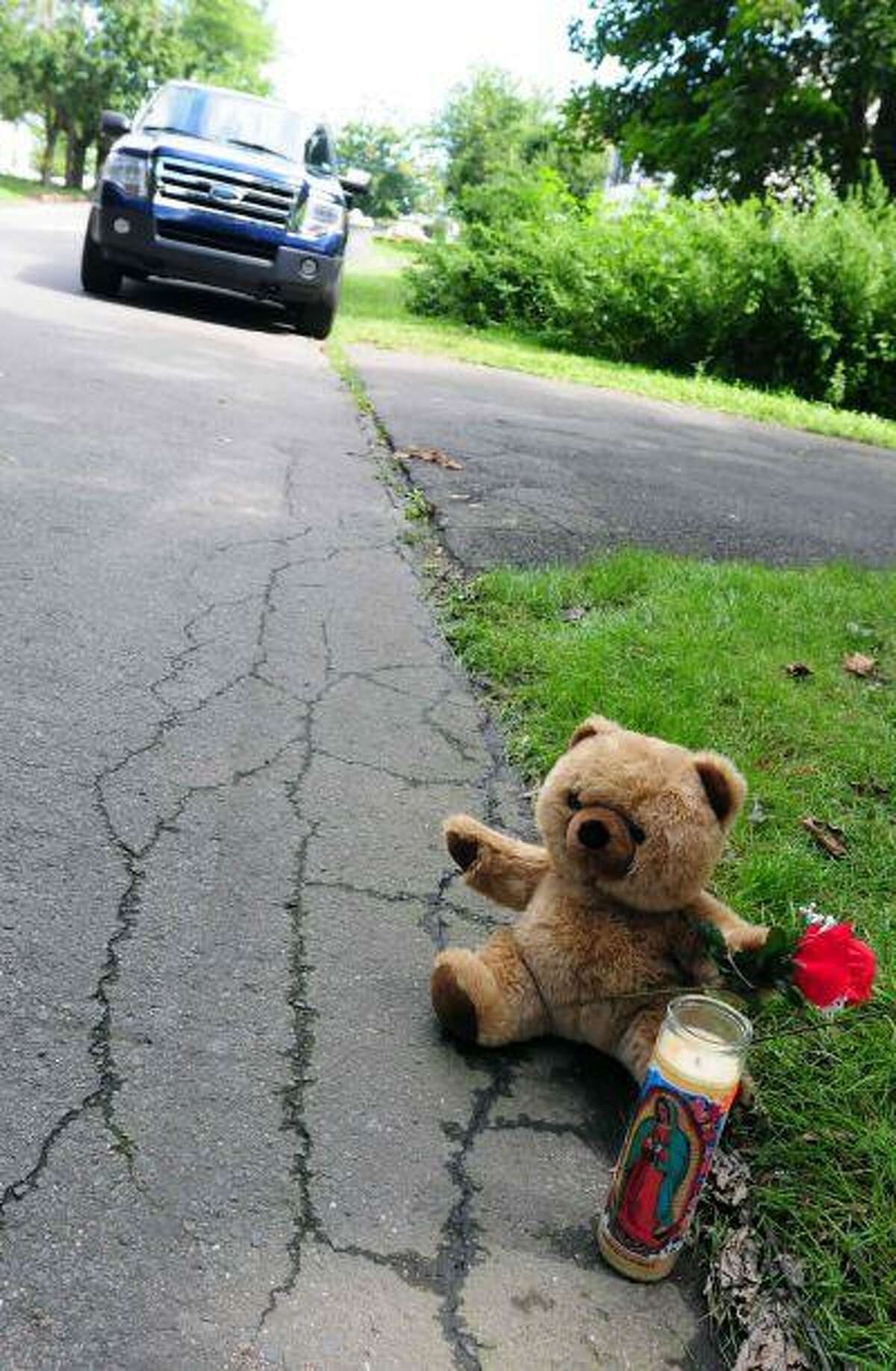 A teddy bear, flower and candle sit near the site on Saturday, Aug. 10, 2013 after a small plane, piloted by Bill Henningsgaard, crashed into two homes Friday in East Haven, Conn. Four people were killed in the incident. (AP Photo/The New Haven Register, Peter Hvizdak)
