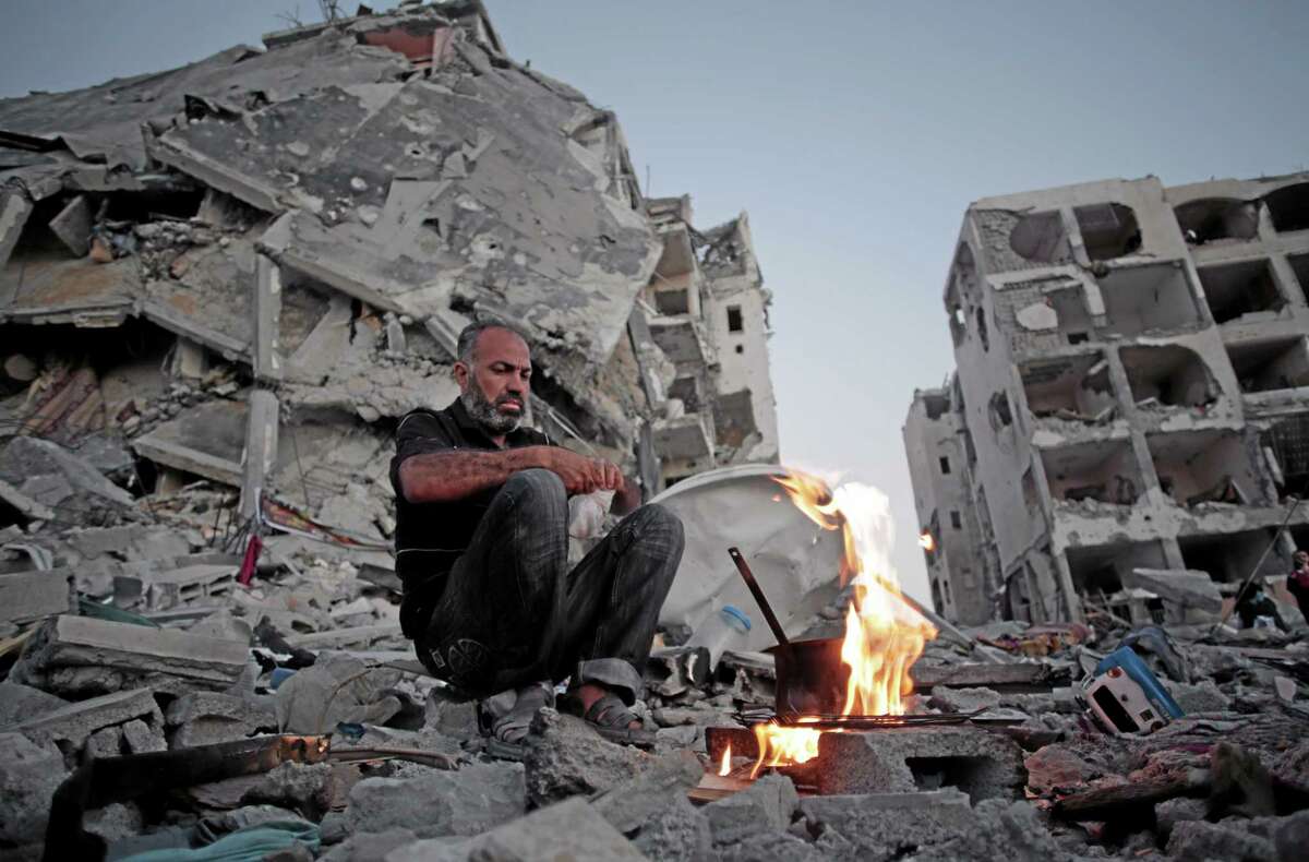 Palestinian Ziad Rizk, 38, makes coffee next to one of the destroyed Nada Towers, where he lost his apartment and clothes shop, in the town of Beit Lahiya, northern Gaza Strip, Monday, Aug. 11, 2014. (AP Photo/Khalil Hamra)
