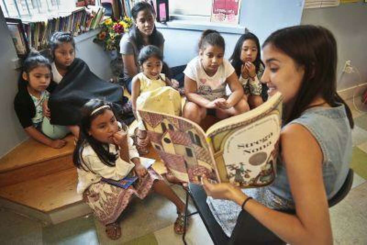 In this Wednesday, Aug. 7, 2013 photo, Sophie Mortner, foreground right, reads aloud for youngsters attending LitCamp, a summer reading program offered through the nonprofit literacy organization LitWorld, in the Harlem neighborhood of New York. "I often times pick and choose the book that I love," said Mortner, a camp counselor who assists with curriculum development. "Often times they choose that book the next day to read." (AP Photo/Bebeto Matthews)