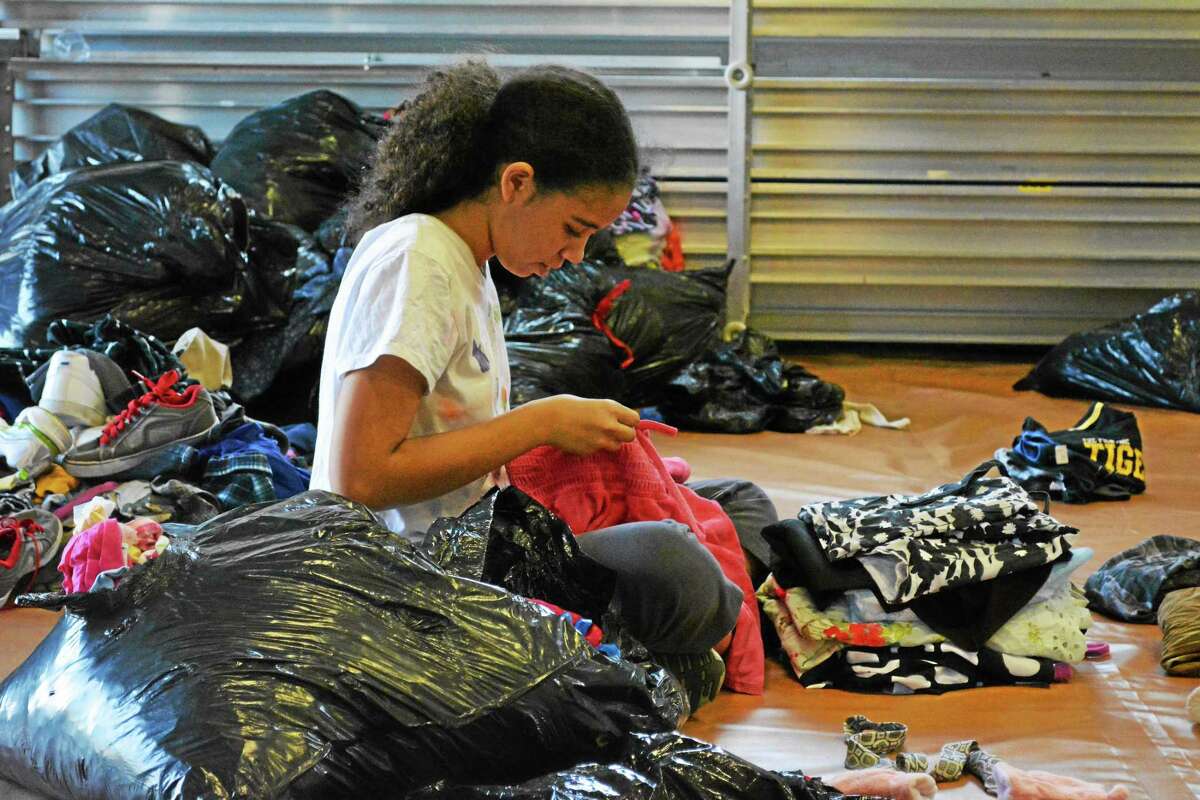 One of the volunteers at the annual Junior Dress for Success event put on by Torrington Early Childhood Collaborative sorts through donated clothes and folds them before dispersing them to the tables arranged by size.