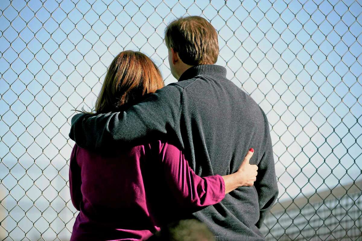 Parents stand along the tennis court fence hoping to see if their child is standing outside on the football field after a gunman was spotted inside Arapahoe High School Friday in Centennial, Colo. Authorities said the gunman shot two students and then turned the gun on himself. School. AP Photo/The Denver Post, John Leyba