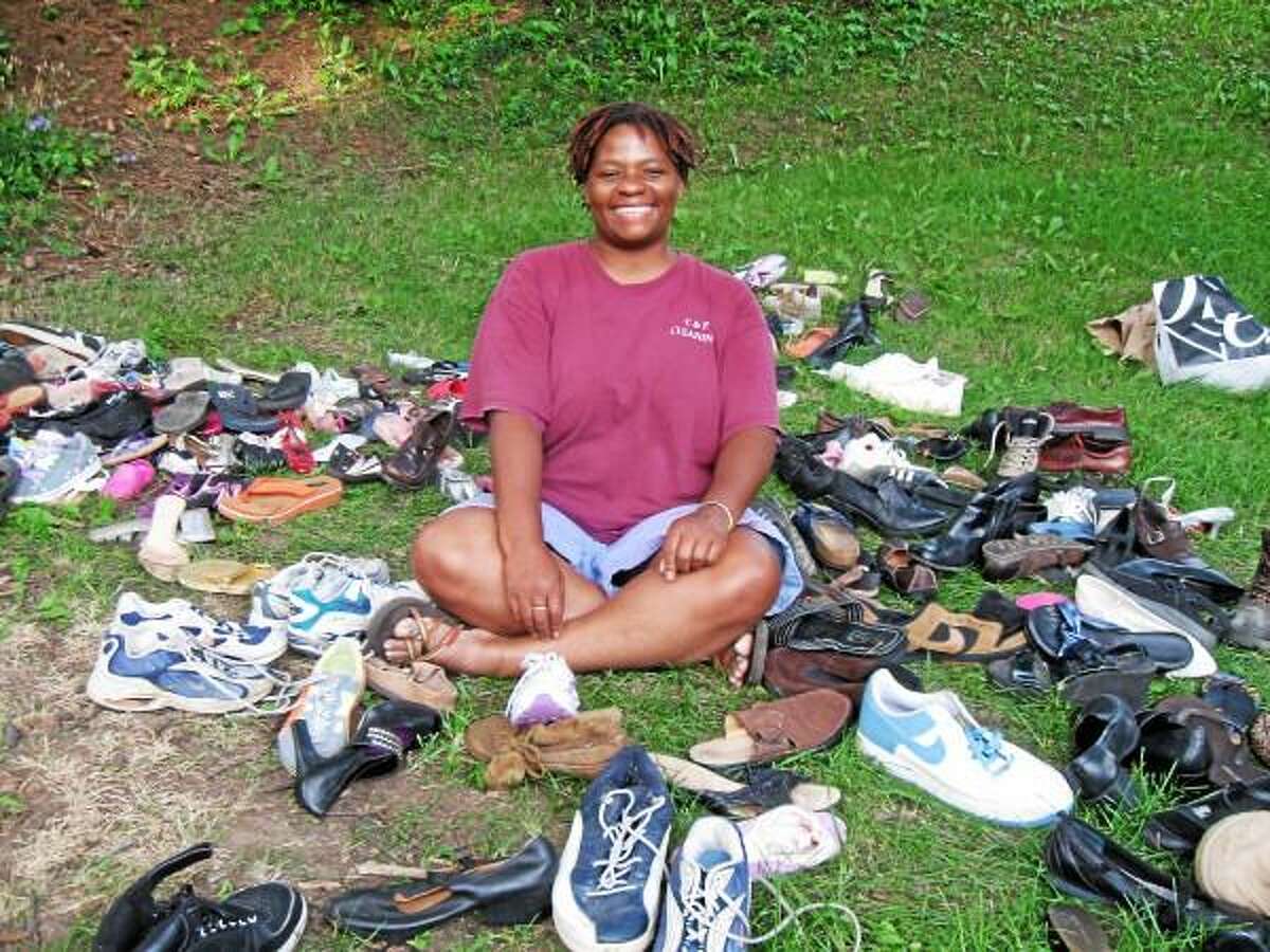 Michelle Pickering sits next to piles of shoes she collected for people in Tanzania. With the help of her friends and various donors, she was able to collect more than30,000 pairs of shoes to send to Tanzania. (Submitted photo)