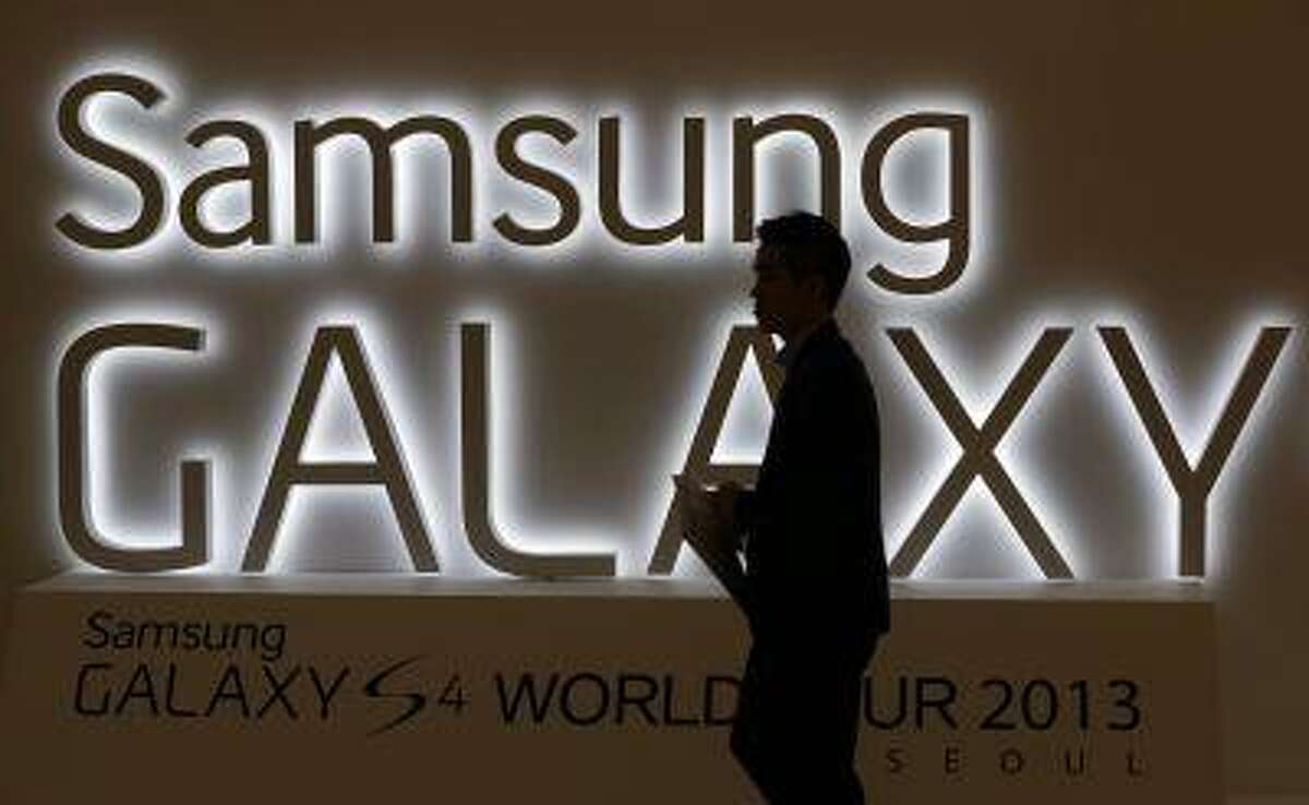 In this photo taken on April 25, 2013, a man walks by a logo of Samsung Electronics Co.'s latest smartphone Galaxy S4 during its unveiling ceremony in Seoul, South Korea. Samsung Electronics Co. has applied for U.S. and South Korean trademarks for a watch that connects to the Internet in the latest sign that consumer technology companies see wearable devices as the future of their business. (AP Photo/Lee Jin-man)