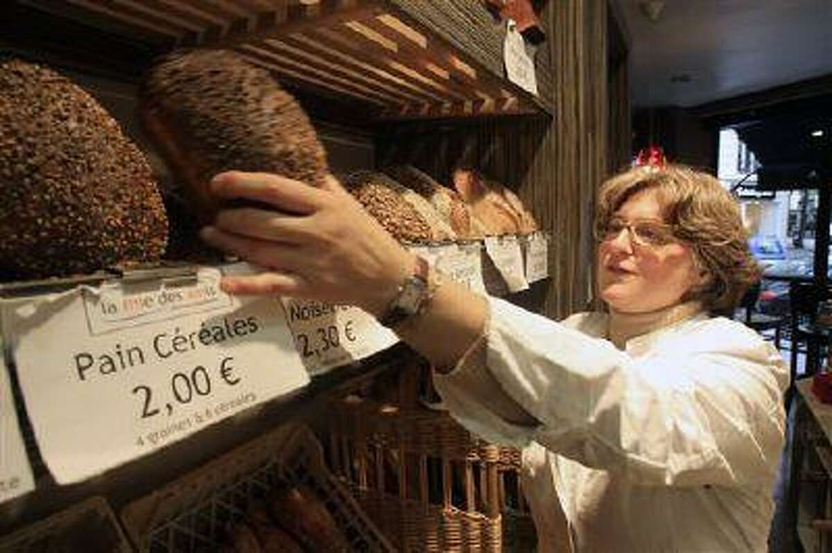 Estelle Levy sets up loaves of bread in her bakery in Paris. France, the country that gave us the words restaurant, bistro and cuisine, is changing how it eats. (Remy de la Mauviniere/AP)