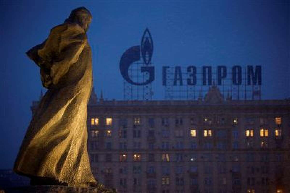 A monument to Ukrainian poet and writer Taras Shevchenko is silhouetted against an apartment building with a sign advertising Russia's natural gas giant Gazprom, in Moscow, Russia, Tuesday, March 4, 2014. Russia's state-controlled natural gas giant Gazprom said Tuesday it will cancel a price discount on gas it sells to Ukraine. Russia had offered the discount in December as part of Russian help for Ukraine. Gazprom also said Ukraine owes it $1.5 billion. (AP Photo/Alexander Zemlianichenko)