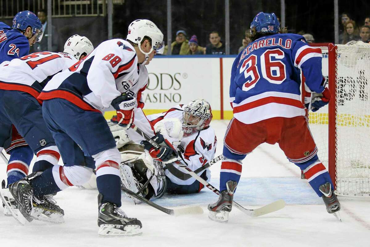 Washington Capitals goalie Philipp Grubauer (31), of Germany, makes a save as Steve Oleksy (61), Nate Schmidt (88), and New York Rangers' Mats Zuccarello (36), of Norway, look on in the second period of an NHL hockey game on Sunday, Dec. 8, 2013, in New York. (AP Photo/John Minchillo)