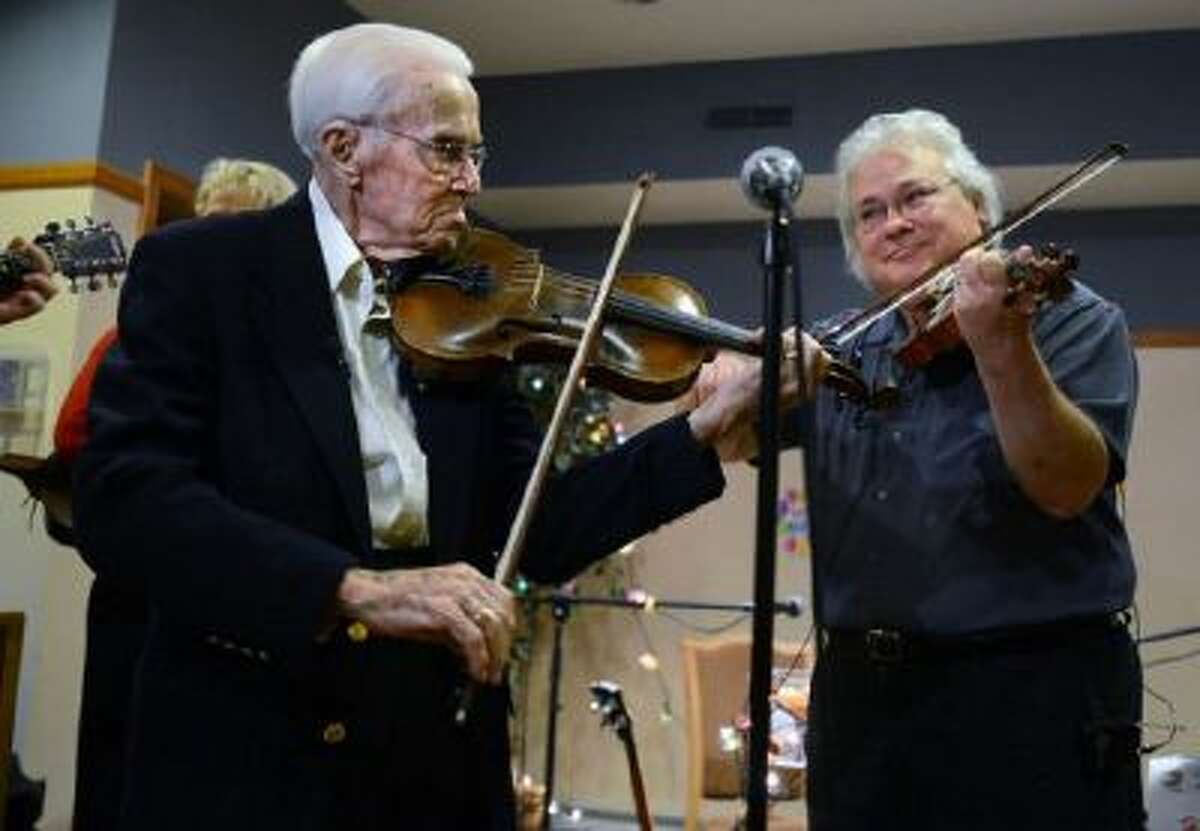 Lloyd Johnson, left, smiles as he plays a tune with renowned musician Peter Ostroushko, for Johnson's 100th birthday on Dec. 4, 2013.
