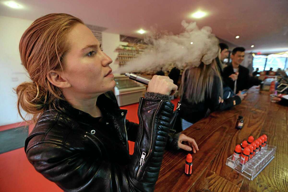 FILE - In this Feb. 20, 2014 photo, Talia Eisenberg, co-founder of the Henley Vaporium, uses her vaping device in New York. Under a New York City law taking effect Tuesday, April 29, 2014, vaporizing devices will be treated the same as a tobacco-based cigarette. The New York ban, along with similar measures in Chicago and Los Angeles and federal regulations proposed last week, are again igniting debate among public health officials, the e-cigarette industry and users lon the future of the popular devices. (AP Photo/Frank Franklin II, File)