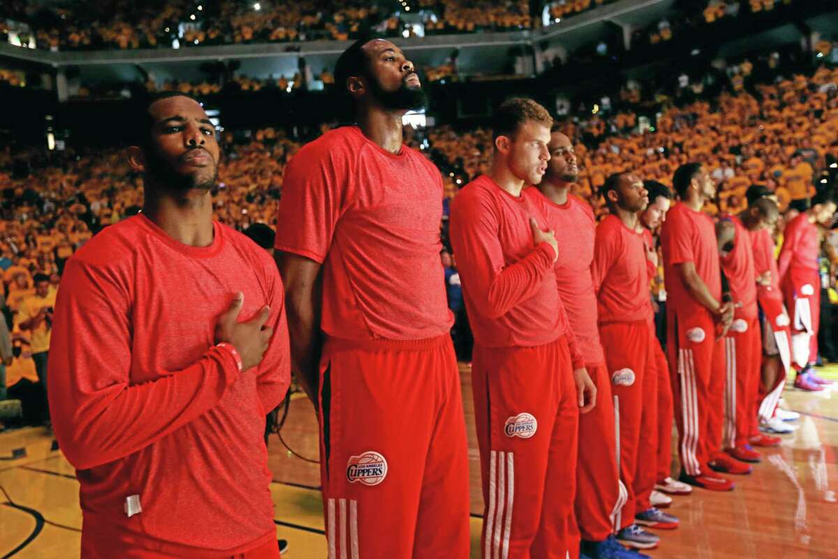 Members of the Los Angeles Clippers listen to the national anthem before Game 4 of an opening-round NBA basketball playoff series against the Golden State Warriors on Sunday, April 27, 2014, in Oakland, Calif. The Clippers chose not to speak publicly about owner Donald Sterling. Instead, they made a silent protest. The players wore their red Clippers' shirts inside out to hide the team's logo. (AP Photo/Marcio Jose Sanchez)