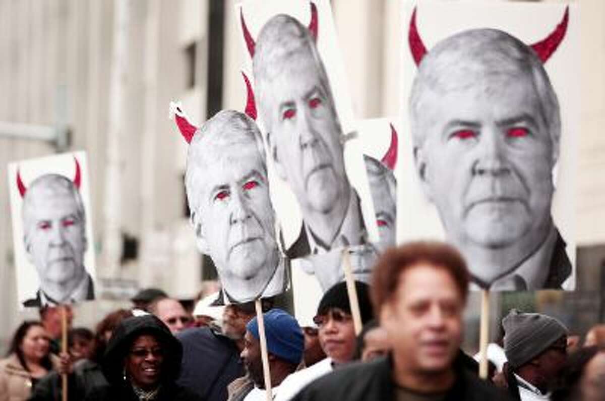 Protestors carry signs that depict Michigan's Governor Rick Snyder as a devil at a rally in front of the U.S. Courthouse in Detroit where Detroit's bankruptcy eligibility trial on Oct. 28, 2013.