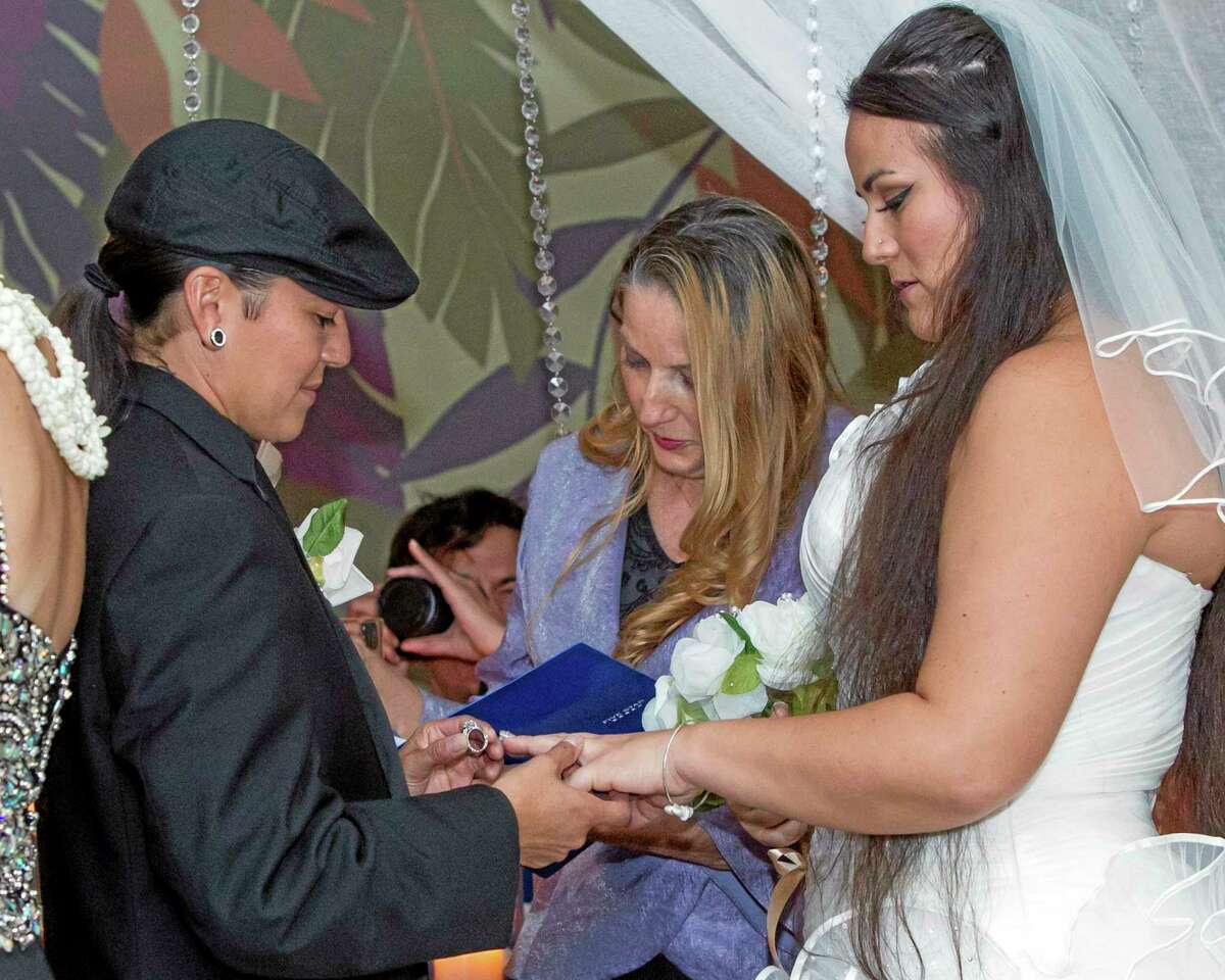 As Rev. Dodi Rose, center, performs the wedding ceremony, Isajah Morales left, places a ring on her partner, Saralyn Morales, during a wedding ceremony at the Sheraton Waikiki, Monday, Dec. 2, 2013 in Honolulu. Hawaii became the 15th state to legalize same-sex marriage Monday, and couples were able to apply for marriage licenses after midnight. After receiving their marriage license, several couples held a group wedding at the hotel. (AP Photo/Marco Garcia)