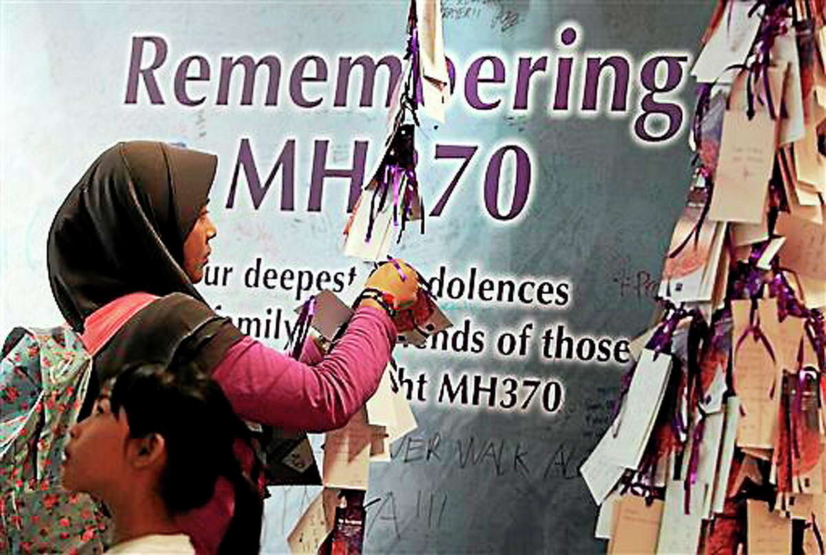 A woman ties a message card for passengers aboard the missing Malaysia Airlines flight MH370, at a shopping mall in Kuala Lumpur, Malaysia, Saturday, April 5, 2014. Search teams racing against time to find the flight recorders from the missing Malaysia Airlines jet crisscrossed another patch of the Indian Ocean on Saturday, four weeks to the day after the airliner vanished. (AP Photo/Lai Seng Sin)