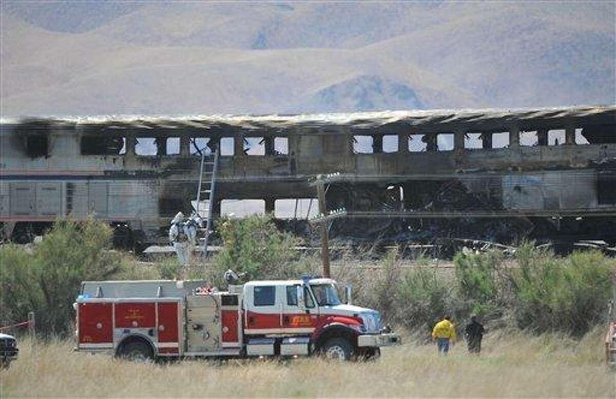Amtrak passenger cars sit still smoldering after the train was struck by a semi truck on US 95 north of Fallon, Nev., Friday June 24, 2011. The driver of the truck and a passenger were killed, and officials must let the wreck cool off before they continue their search. (AP Photo/Liz Margerum - Reno Gazette Journal)