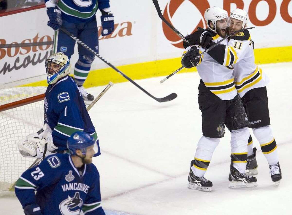 ASSOCIATED PRESS Boston Bruins center Patrice Bergeron celebrates with Gregory Campbell, right, after scoring on Vancouver Canucks goalie Roberto Luongo (1) as Canucks defenseman Alexander Edler (23) skates nearby during the second period of Game 7 of the Stanley Cup Finals on Wednesday in Vancouver, British Columbia.