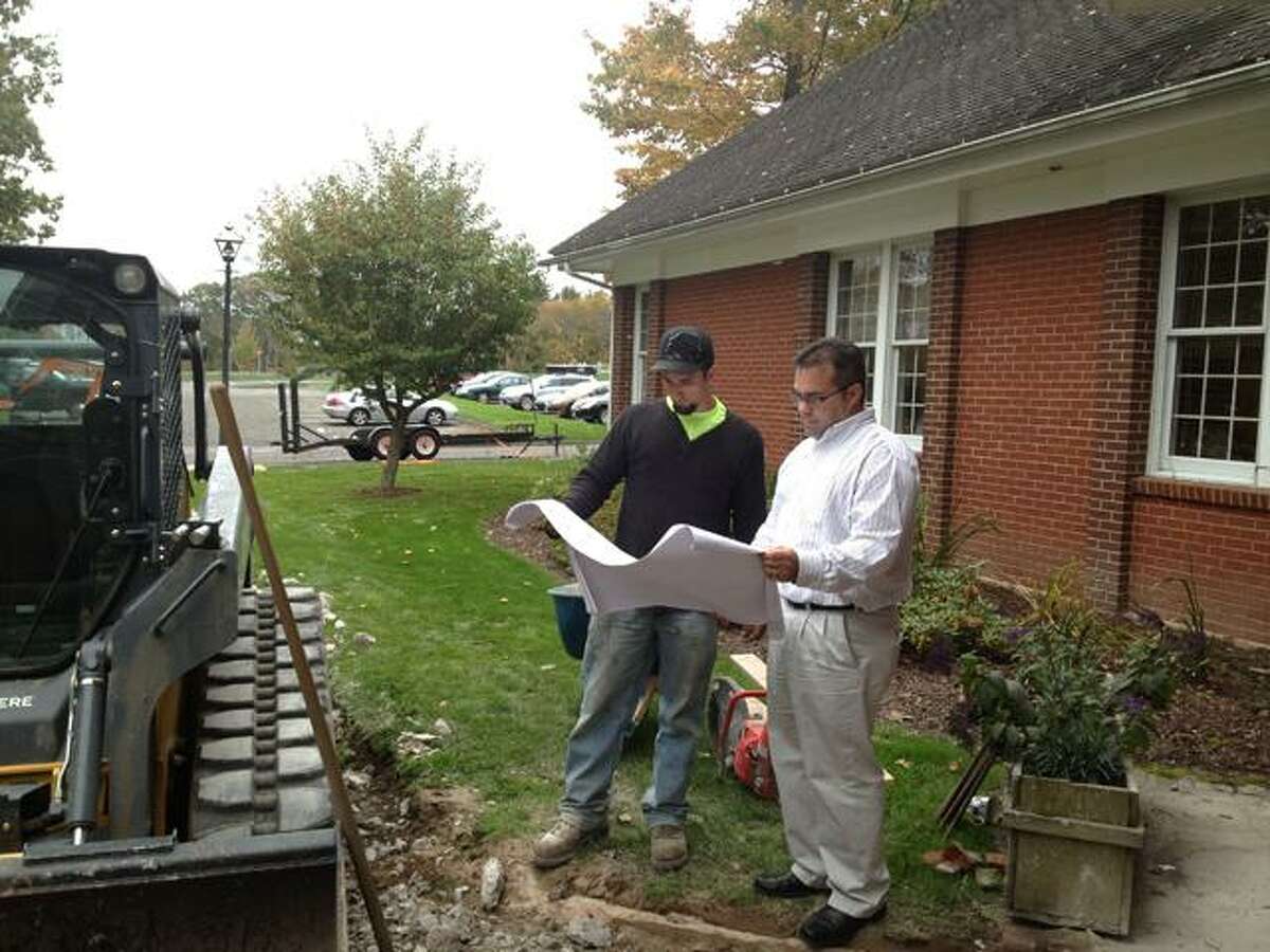 Sarah Bogues/The Register Citizen Tyler Reidhard, owner of T.R. Designs, and Harwinton First Selectman Mike Kriss look at blue prints for the sidewalk repair project at town hall.
