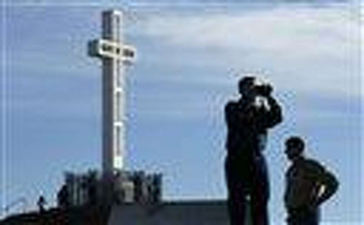 In this 2011 file photo, Rev. John Fredericksen of Orlando, Fla., alongside Burdette Streeter of San Diego, takes a picture in front of the war memorial cross on Mount Soledad in San Diego. Supporters of the war memorial, which is on public land in San Diego, are planning to ask the Supreme Court to reverse a federal court's decision deeming the cross unconstitutional. Associated Press