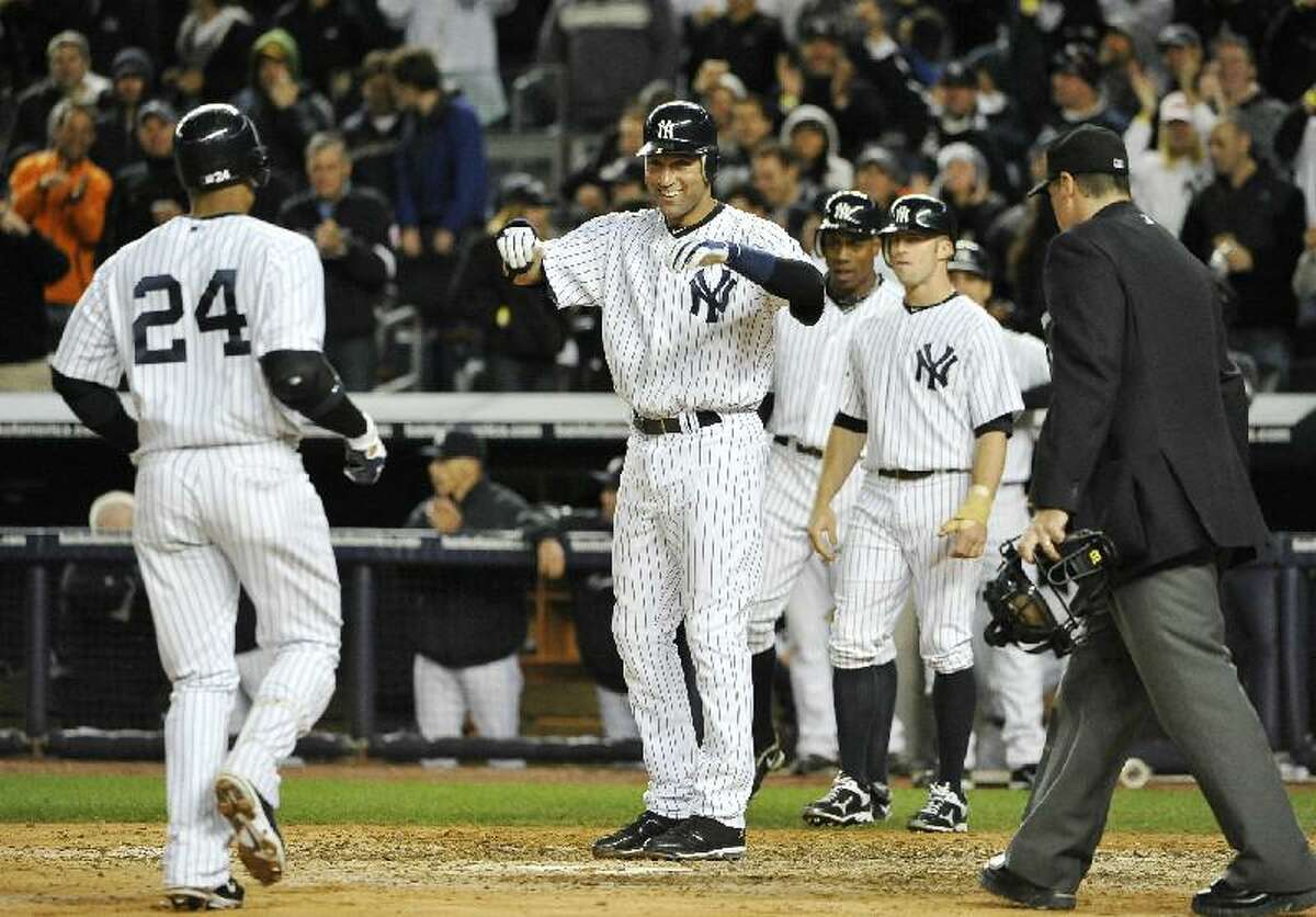 ASSOCIATED PRESS New York Yankees shortstop Derek Jeter, center, greets Robinson Cano at home plate after Cano hit a grand slam off Detroit Tigers relief pitcher Al Alburquerque that scored Jeter, Brett Gardner and Curtis Granderson in the sixth inning during the continuation of Game 1 of their American League division series on Saturday at Yankee Stadium in New York.