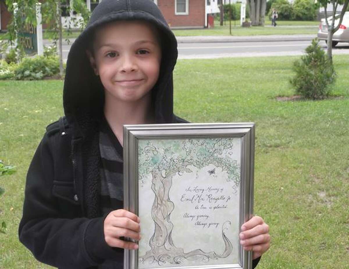 Southwest School second grader Remi DeSmith holds up a plaque dedicating an evergreen outside the school to Emil "Moe" Renzullo's family. Renzullo passed away in 2010. (MICHELLE MERLIN / Register Citizen)