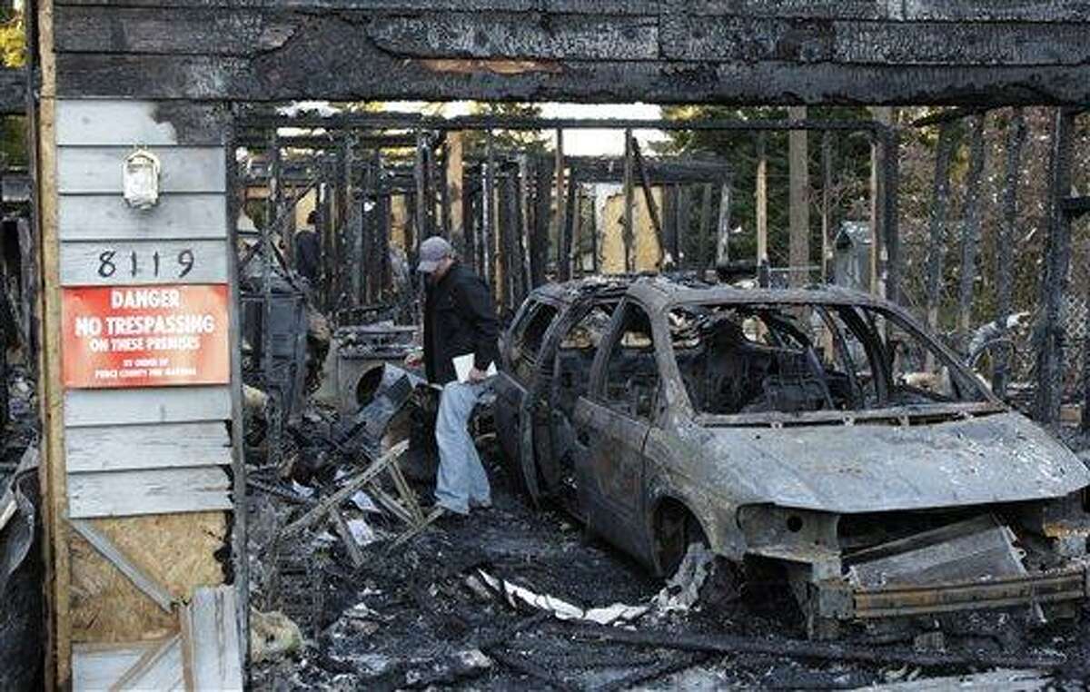 In this photo provided by the Pierce County Sheriff's Dept., an investigator walks through the garage area, Monday in the rubble of the home in Graham, Wash., where Josh Powell and his two sons were killed Sunday in what police said appeared to be a deliberately set fire. Powell's wife Susan went mysteriously missing from their West Valley City, Utah, home in December 2009. Associated Press