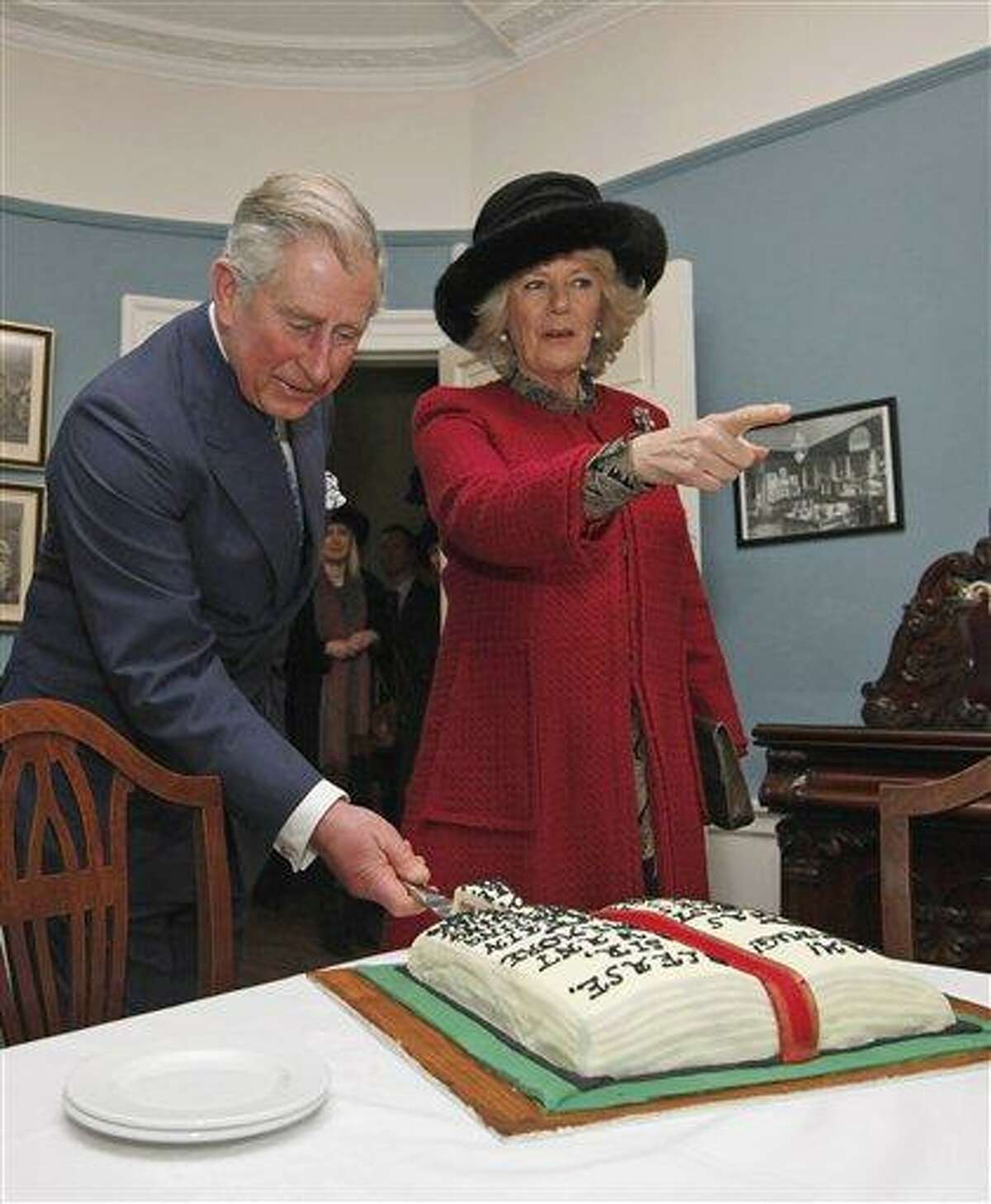 Britain's Prince Charles cuts a birthday cake in honor of Charles Dickens as he stands with his wife Camilla, Duchess of Cornwall, right, at the Dickens Museum in London Tuesday. Associated Press