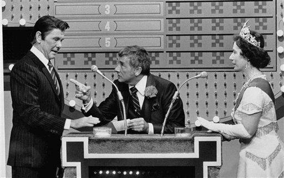 In this Nov. 5, 1982 file photo provided by NBC-TV, "Family Feud" host Richard Dawson, center, gives President Reagan, played by "Tonight Show" host Johnny Carson, a chance at the big money as Queen Elizabeth (Rose Carr) readies herself at the buzzer during "International Family Feud" sketch on the show in Burbank, Calif. The "feud" pitted the Reagans against the Windsor family. Associated Press