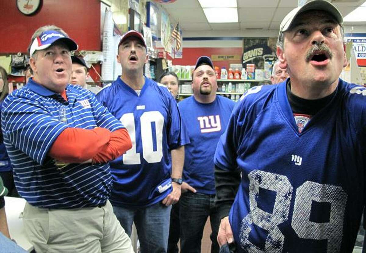 DEBBIE MORELLO/Register Citizen Tony Renzullo (right) owns Carbone's Market. He was closed for business but held a Super Bowl party for friends and family on Sunday -- all are diehard Giants fans. Tom Jacquot (far left) City Councilman Drake Waldron (2nd to left) Eric Renzullo (back) and Tony Renzullo react to a play in the first quarter.