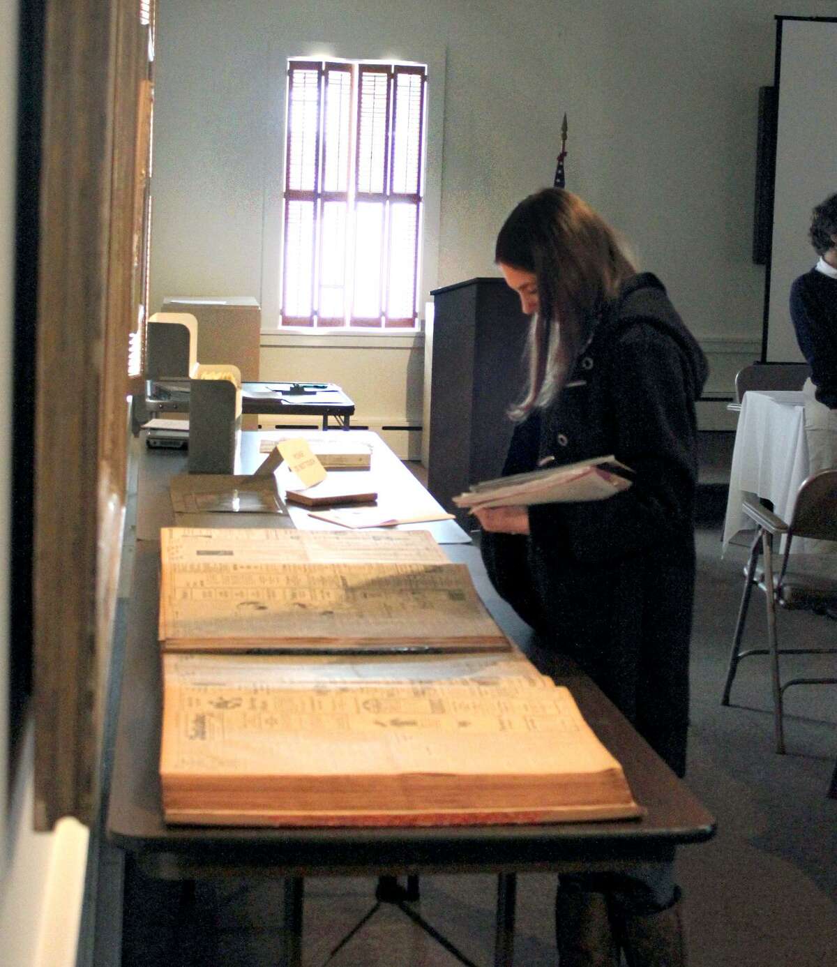 A student visiting the Torrington Historical Society looks over bound copies of vintage newspapers.