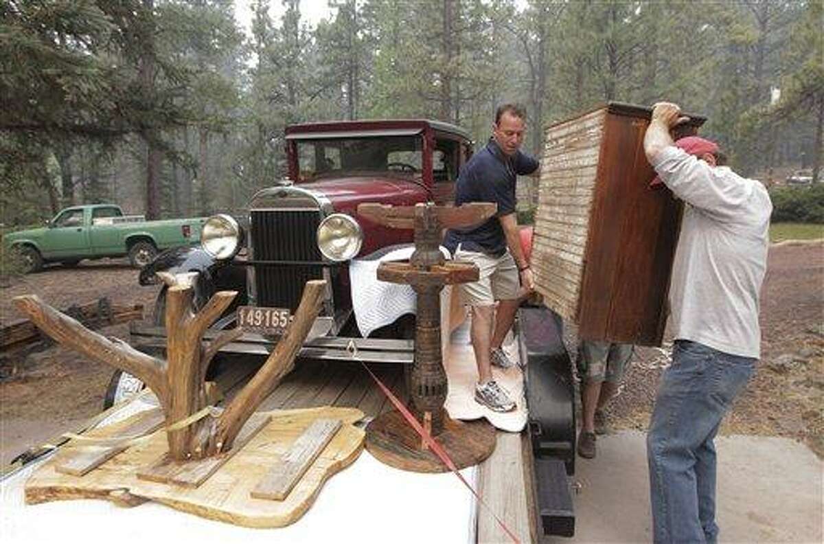 A 1928 Oldsmobile sedan sits in a flatbed trailer as Allan Johnson, right, and Larry Duffy move furniture as they evacuate their home in Greer, Ariz., Sunday, June 5, 2011. Crews used controlled backfires early Sunday to blunt the advance of a major wildfire near mountain communities in eastern Arizona, a blaze termed "absolutely frightening" by the state's governor that has already burned through 225 square miles of forest and brush. (AP Photo/Jae C. Hong)