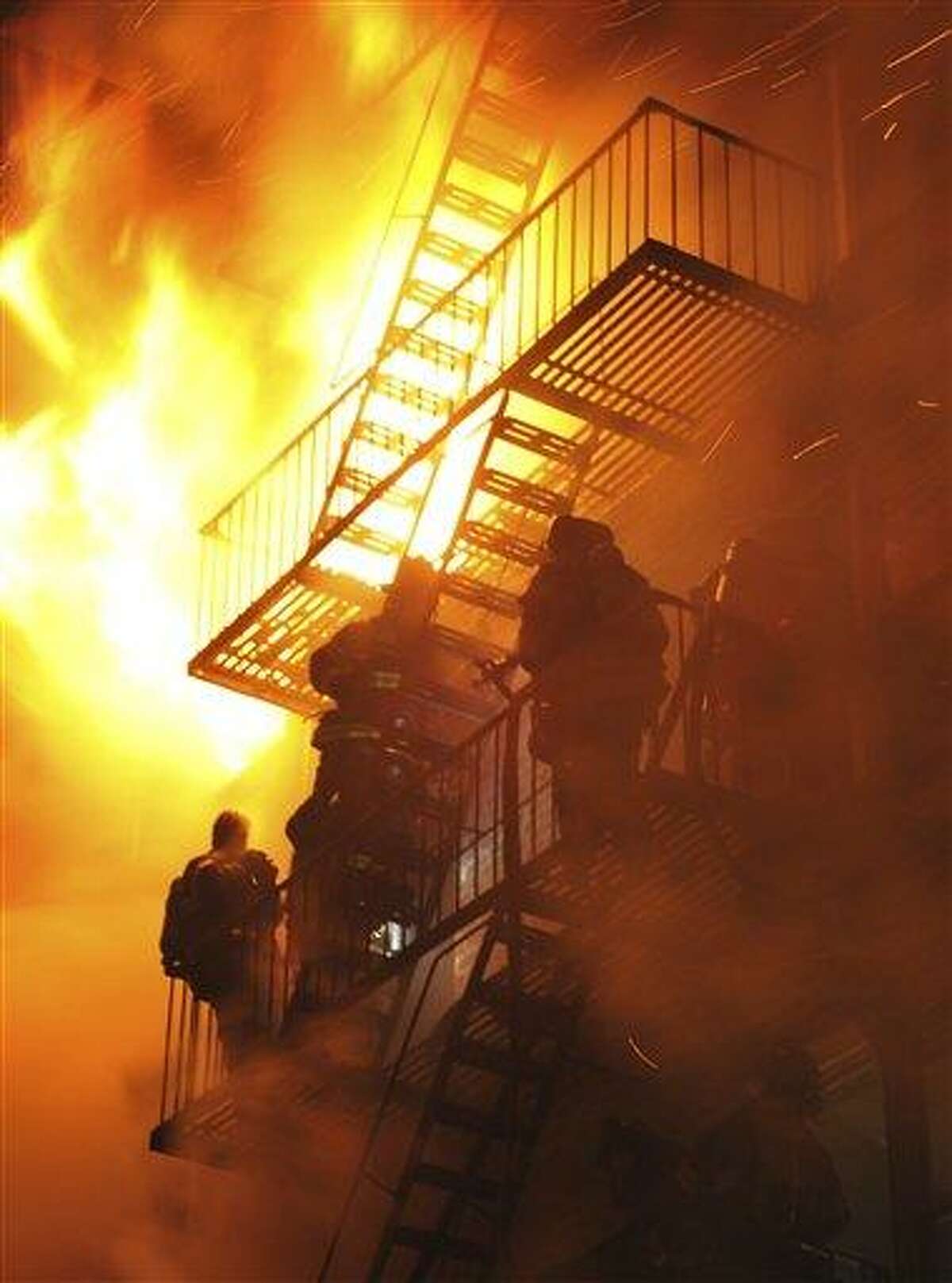 Firefighters stand on the fire escape as winds whip the flames from a five-alarm fire in the Brooklyn borough of New York late Saturday Feb. 19, 2011. Strong winds have meant several hours of work for hundreds of New York City firefighters trying to extinguish a fire that ripped through a six-story apartment building. A fire department spokesman says at least 20 firefighters have been injured while battling Saturday's (AP Photo/Paul Martinka)