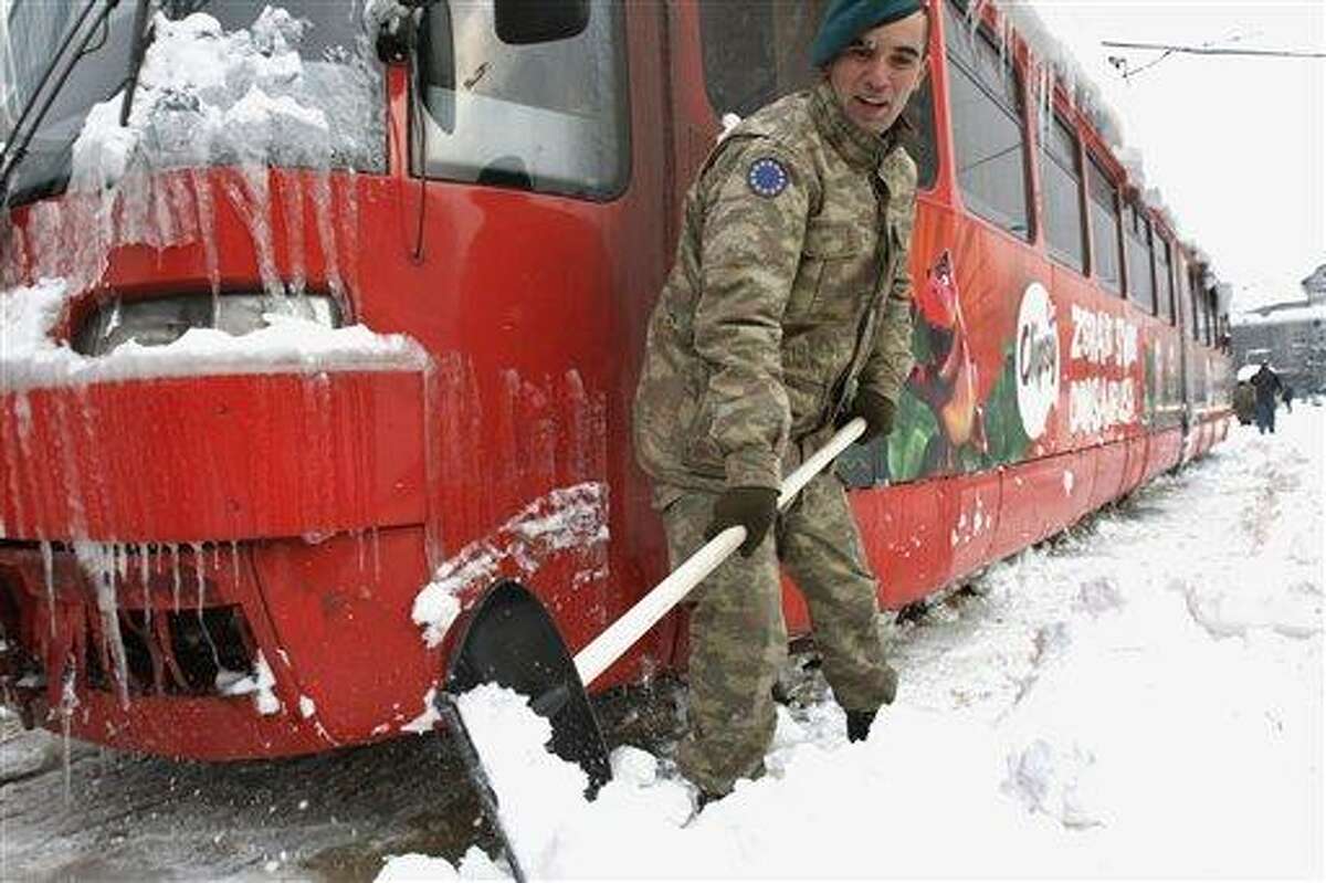 Turkish soldiers members of the European Union Force in Bosnia and Herzegovina, EUFOR, shovel snow from the tracks around a frozen tram as they work to normalize public transport in Bosnian capital of Sarajevo Sunday. Bosnia's government declared a state of emergency in its capital Saturday after Sarajevo was paralyzed by snow. Associated Press